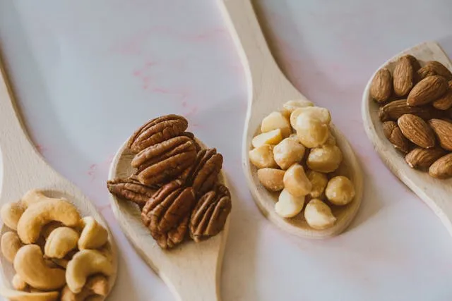 Wooden spoons filled with various nuts, emphasizing their natural textures and earthy tones.